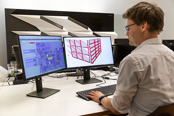 Stefan Huth sitzt am Schreibtisch vor zwei großen Bildschirmen, die Algorithmen zeigen