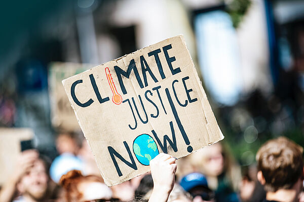 Climate Justice Now Eine Person trägt auf einer Demonstration ein Plakat mit dem Schriftzug "Climate Justice Now!"