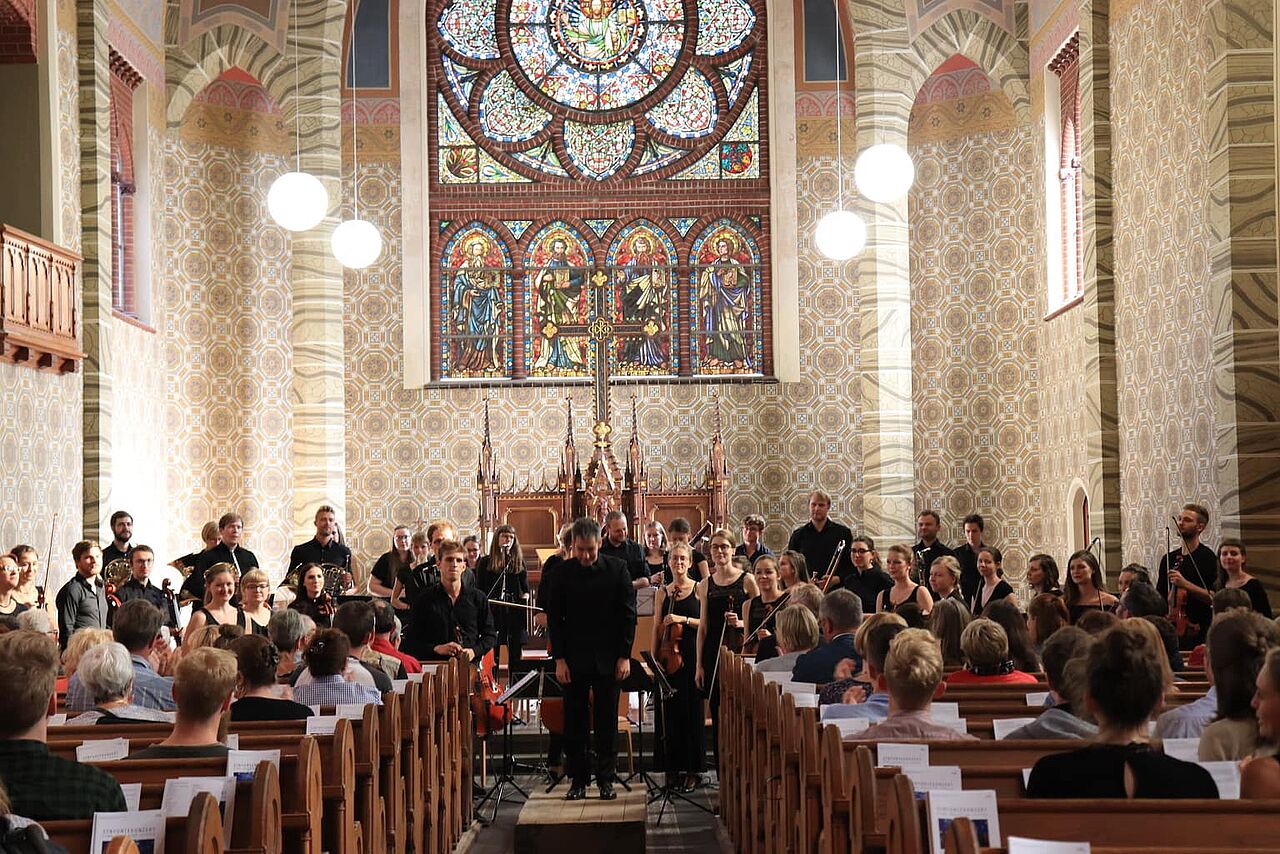 Das Sinfonieorcherster der HTWK beim Spielen in einer Kirche.