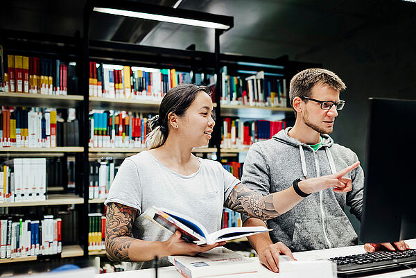 Eine Studentin zeigt einem Kommilitonen etwas auf einem Computerbildschirm