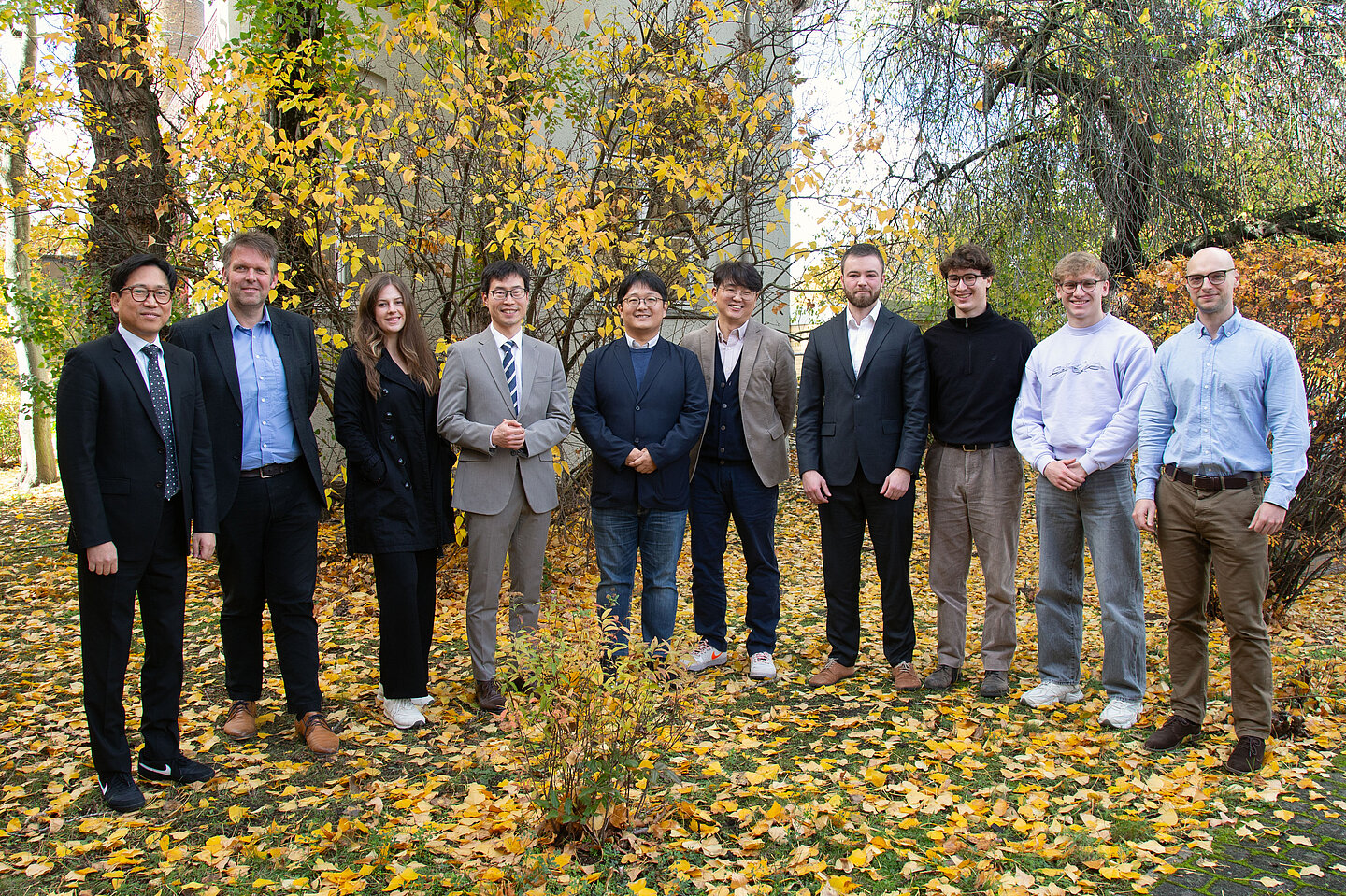 Gruppenfoto 9 Männer und 1 Frau stehen für ein Gruppenbild nebeneinander
