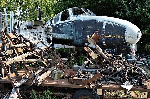 EuReCOMP Zerstörtes Flugzeug im Hintergrund und alte Flugzeugteile im Vordergrund