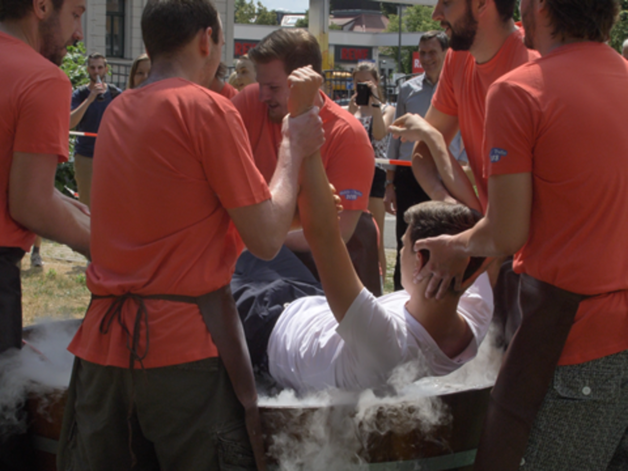 Studierenden tauchen einen weiteren Studenten in ein mit Wasser gefülltes Fass. Sie feiern das Gautschfest.