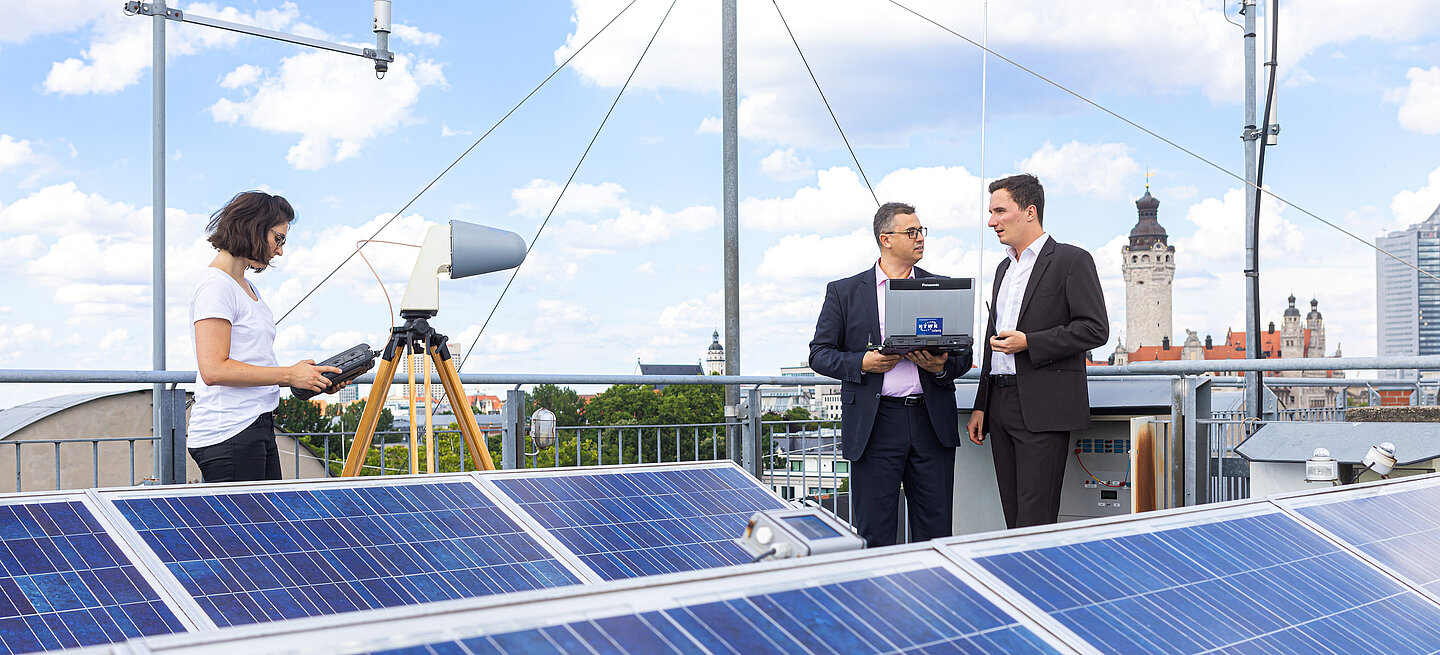 Three people work with solar systems on one roof
