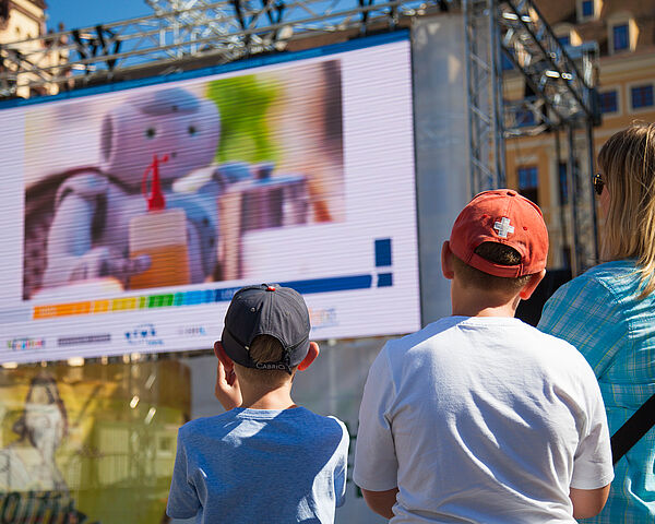 Familie blickt auf die Projektion eines Roboters des HTWK NAO-Teams am Leipziger Marktplatz