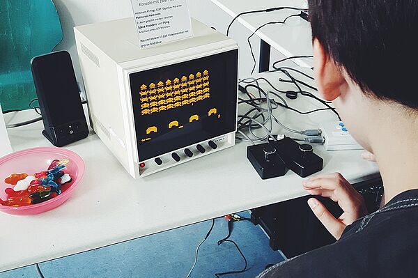 Ein Junge sitzt am Tisch und spielt ein Computerspiel