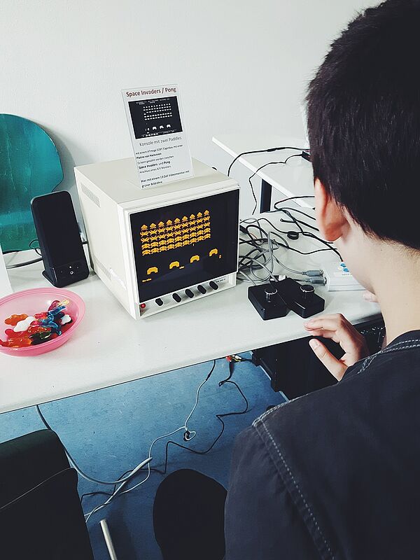 Ein Junge sitzt am Tisch und spielt ein Computerspiel