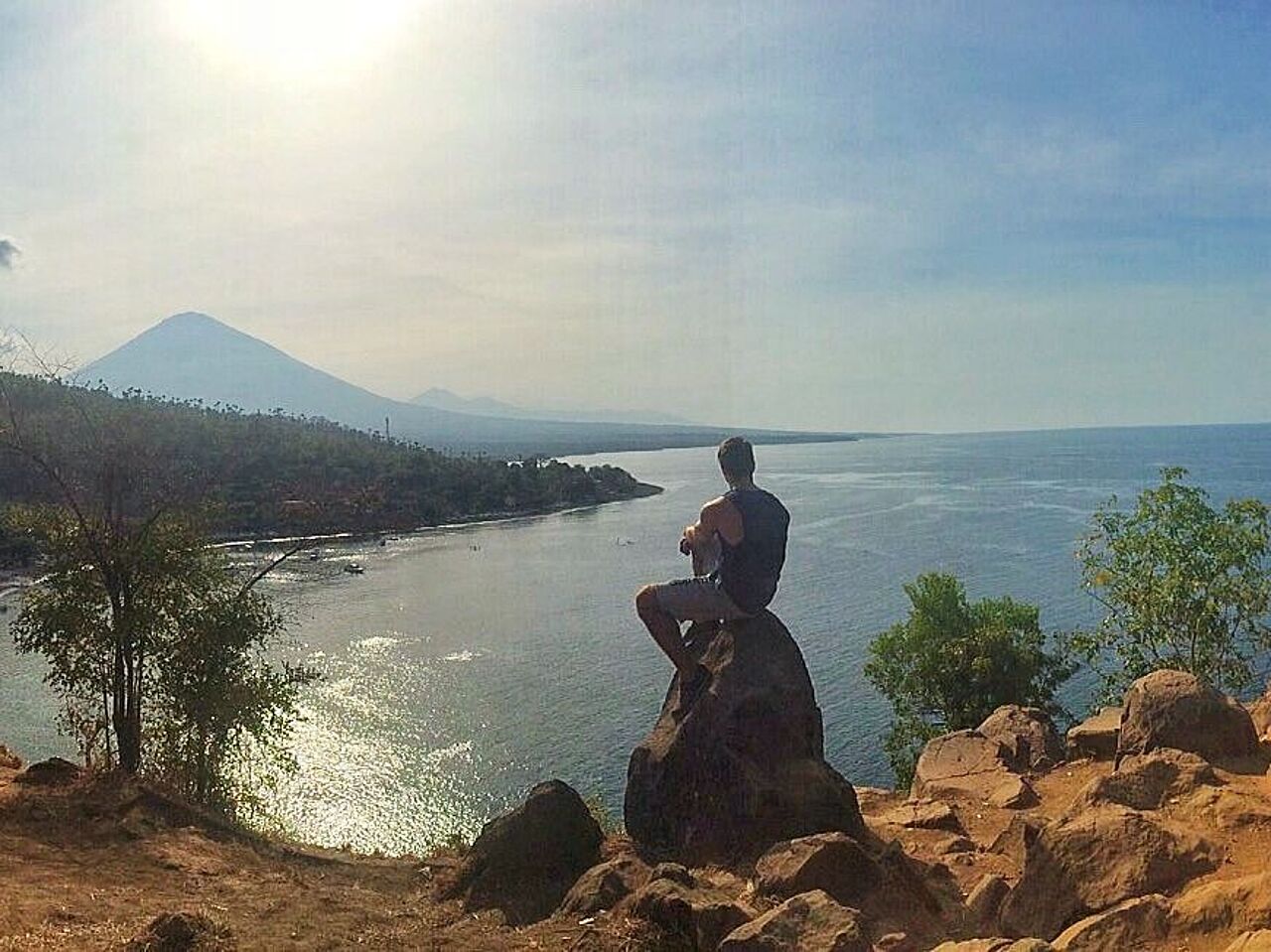 Blick auf eine Meeresbucht auf Bali. Am Horizont sind Berge zu sehen.