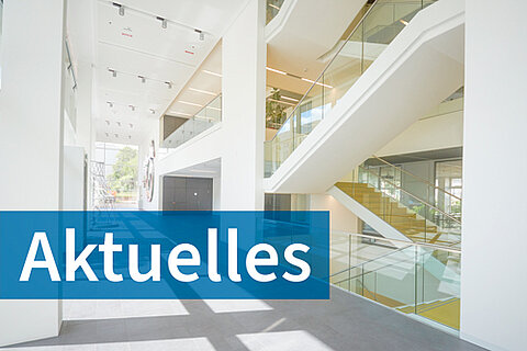 Vorraum mit Treppen im Nieper-Bau der HTWK Leipzig bei Tageslicht, davor der Schriftzug Aktuelles