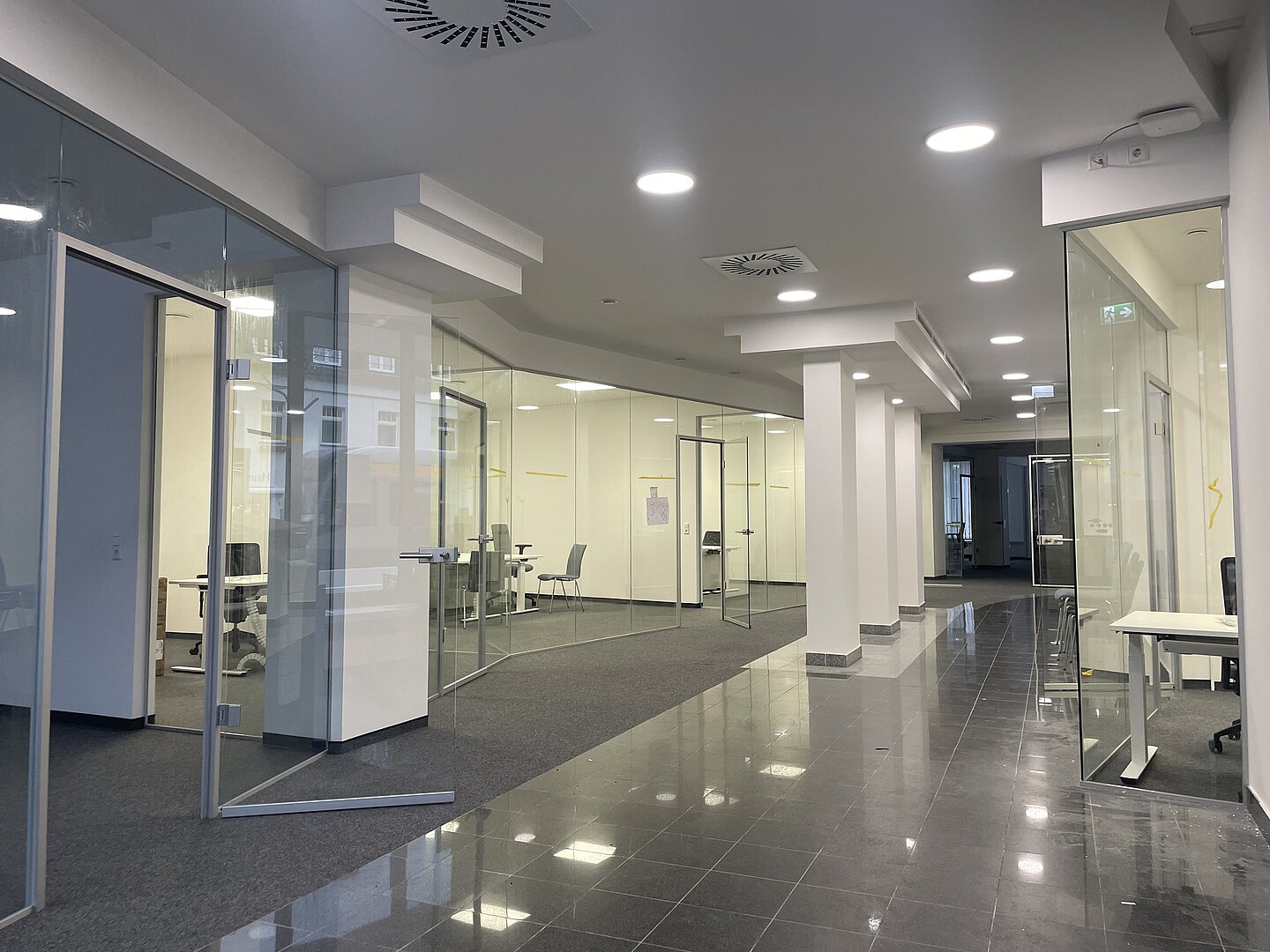 Innenansicht des modernen City Offices mit vielen Glaswänden und weißen Säulen.
