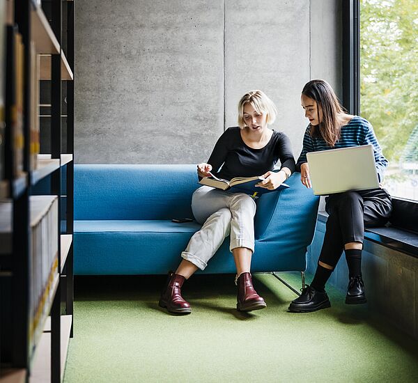 zwei Personen sitzen mit Laptop zusammen