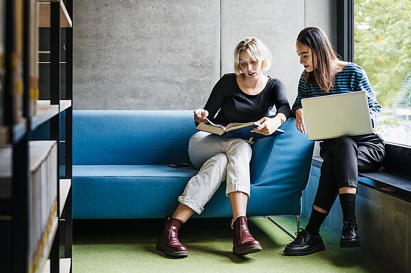 zwei Personen sitzen mit Laptop zusammen