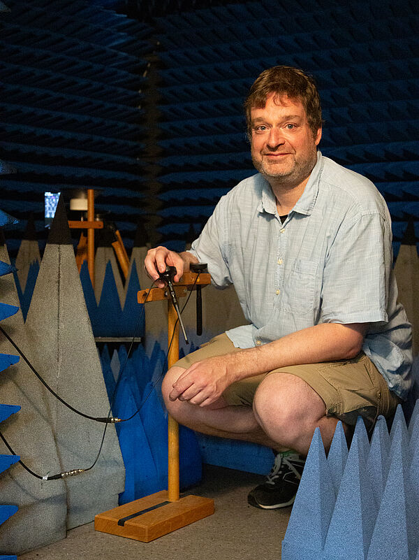 Prof. Robert Geise instaliert Antennen einer mobilen Basisstation in der Absorberkammer. Er hockt und hält eine Antenne in der Hand
