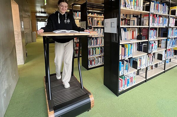 Eine Studentin geht auf dem Laufband in der Bibliothek.