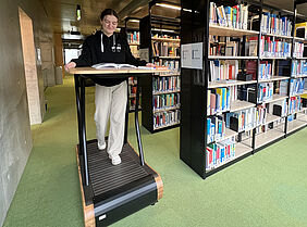 Eine Studentin geht auf dem Laufband in der Bibliothek.