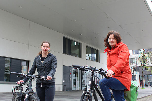 Zwei Frauen mit Fahrrädern vor der Hochschulbibliothek
