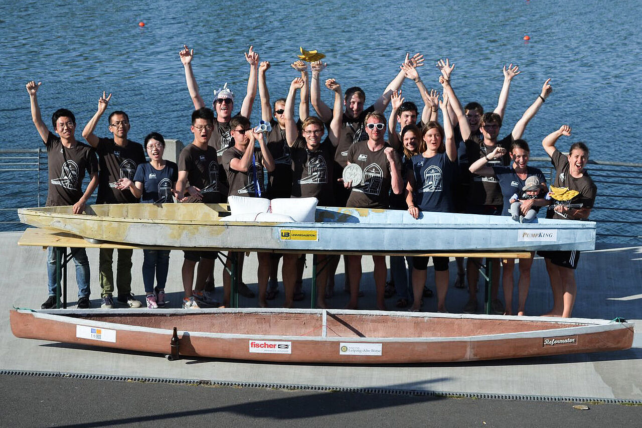 Group picture of the concrete canoe team in front of a river with a canoe