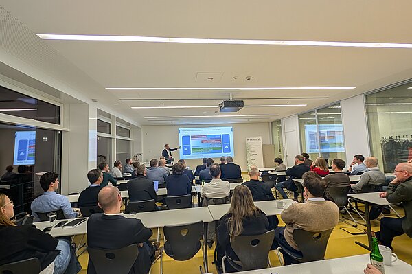 Gruppe von Menschen in Seminarraum hört Vortrag zu