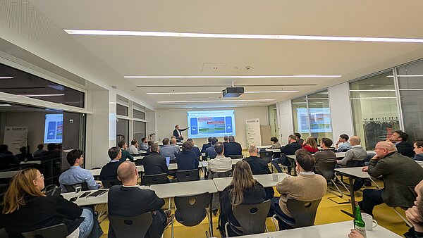 Gruppe von Menschen in Seminarraum hört Vortrag zu