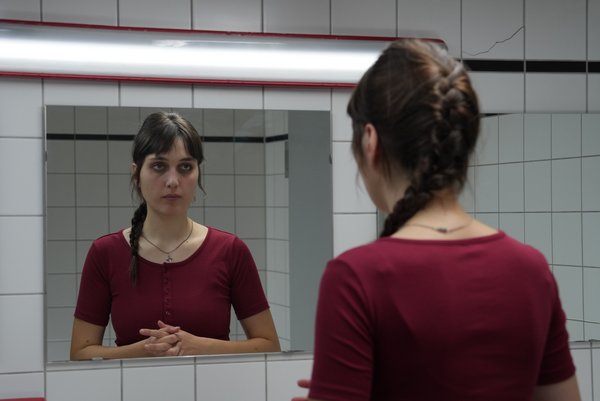 Marleen Müller als Hanna beziehungsweise Annah (Foto: Johann Verlohren/HTWK Leipzig) Frau in rotem Shirt steht vor Spiegel und blickt hinein