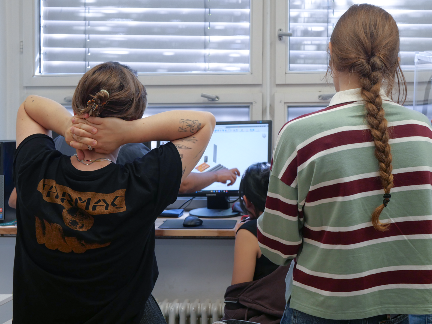 Mehrere Personen stehen vor einem Bildschirm, auf dem eine technische Zeichnung zu sehen ist.