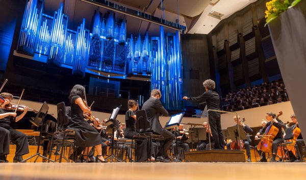 Feierliche Immatrikulation 2026 Orchester spielt auf großer Bühne vor blau beleuchteter Orgel