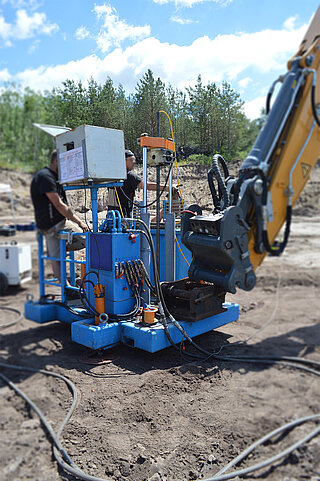 GeoCheck Two people are operating a piece of equipment for geotechnical soil testing outdoors