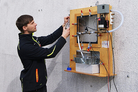 SONY DSC Mann bedient ein techniches Modell an einer Wand