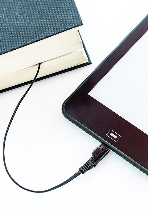 Illustration eines Buches und Handys, welche mit einem Kabel miteinander verbunden sind.