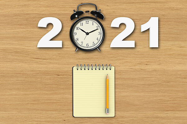 2021 Änderungen Auf einem Schreibtisch liegende Jahreszahl 2021 in dem die "0" mit einer Uhr dargestellt wird und einem Notizblock