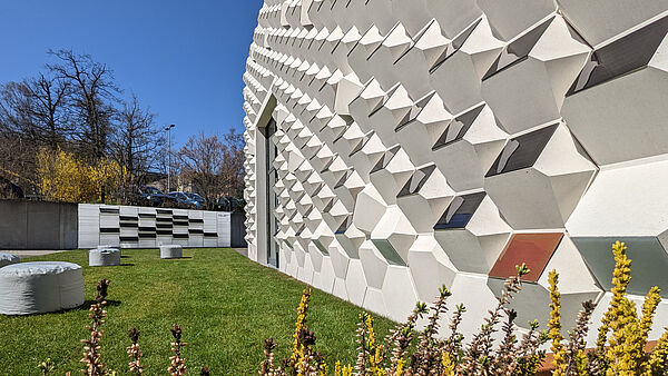 Eine Betonfassade mit Photovoltaik-Elementen auf einer grünen Wiese