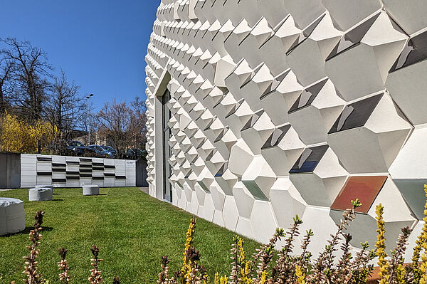 Eine Betonfassade mit Photovoltaik-Elementen auf einer grünen Wiese