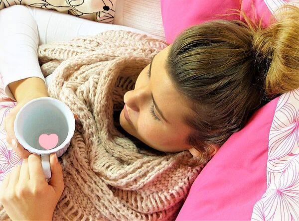 junge Frau mit Tee im Bett