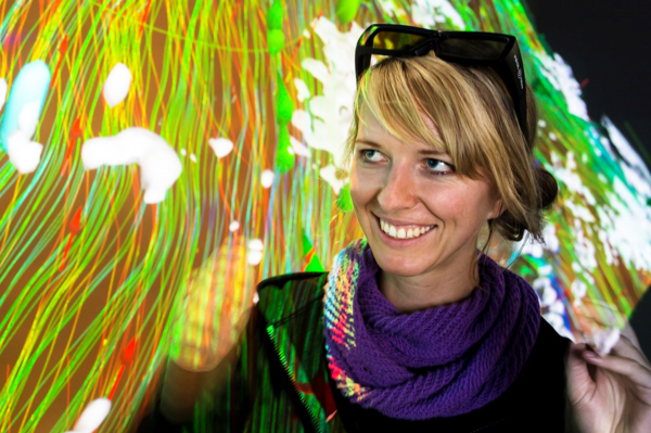 Auf dem Bild steht Prof.in Dr.in Carolin Helbig vor einem farbigen Lichtervorhang