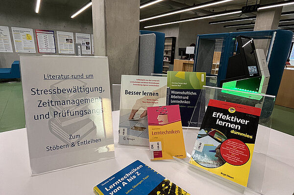 Ein Tisch mit Büchern aus dem Bibliotheksbestand und dem Hinweis, dass alle entleihbar sind. Thematisiert werden vor allem Lernstrategien.