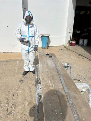 Ein Mann in Schutzkleidung steht neben langen Brettern aus recyceltem Rotorblatt