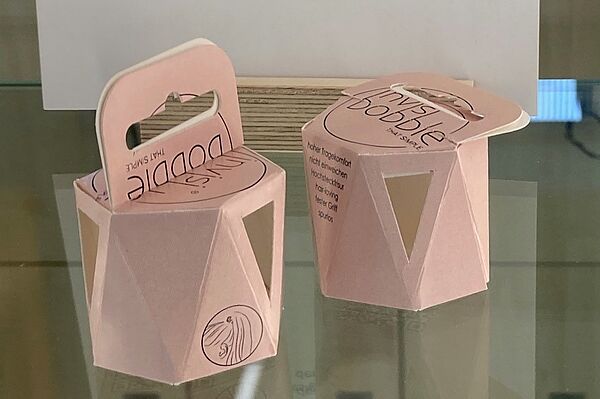 Sechseckige Pappschachteln in Rosa, raffiniert gefaltet, mit Henkel.