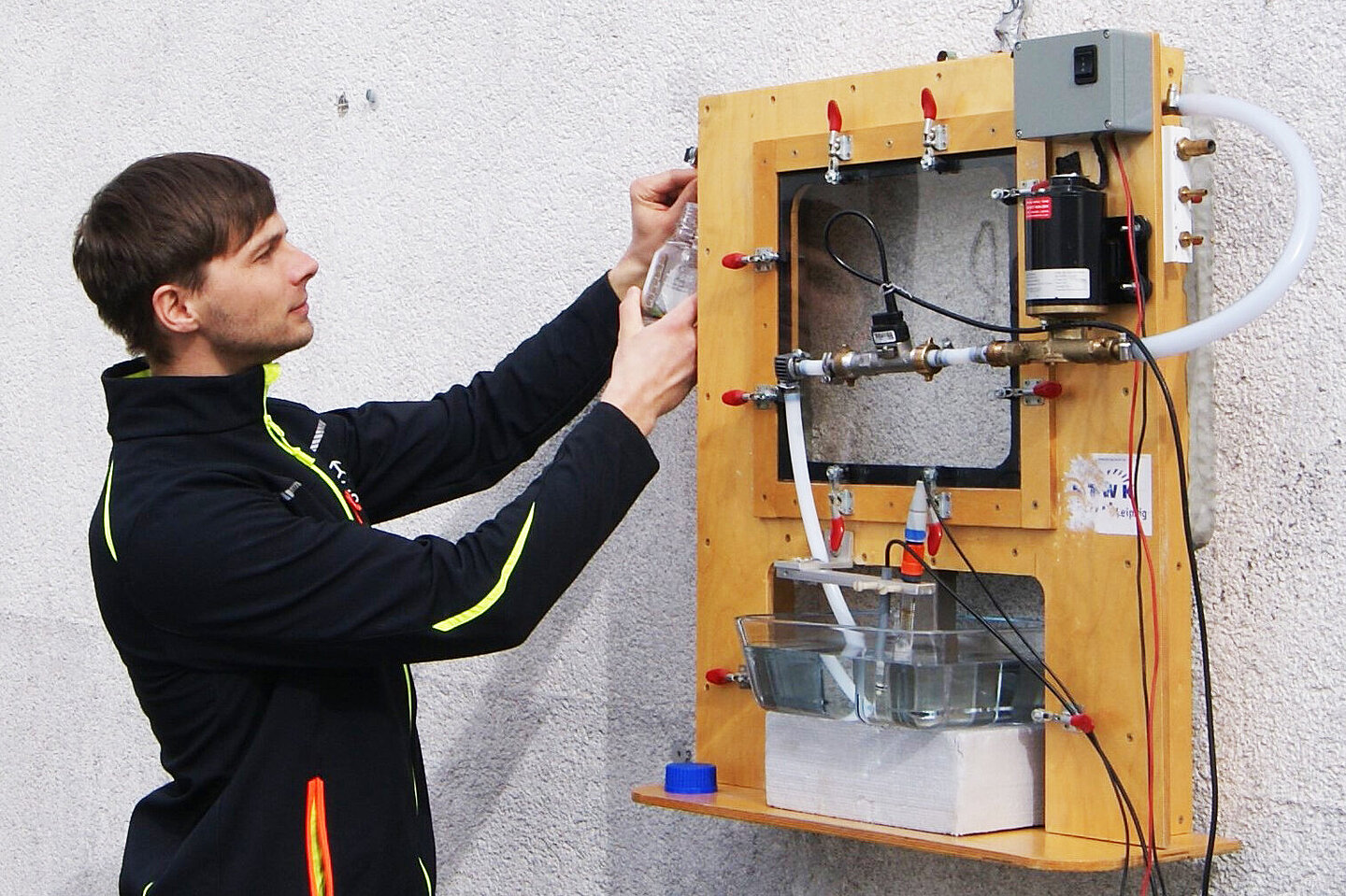 A man is operating a technical model mounted on a wall