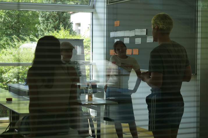 Blick durch Seminarfenster in Seminarraum mit Schülern an der Tafel