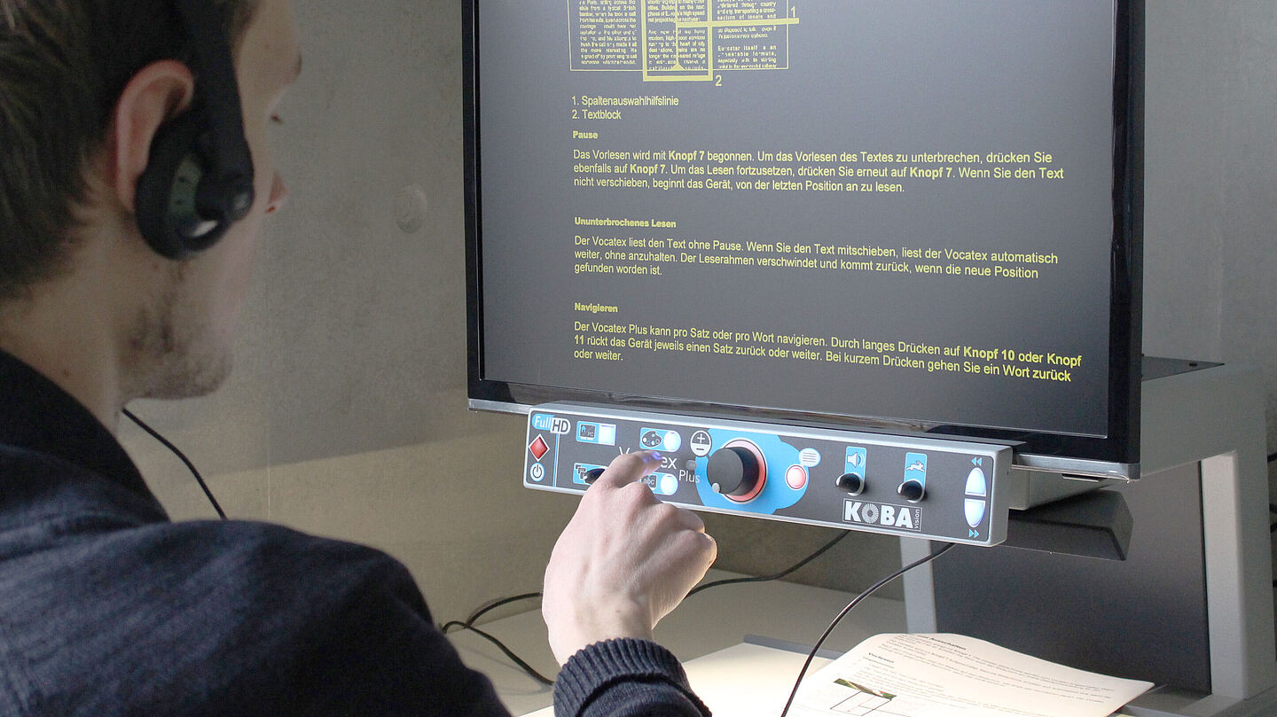 Arbeitsplatz mit Vergrößerung und Vorlesesystem für Printmedien Nutzer mit Kopfhörern am Arbeitsplatz mit Vergrößerung und Vorlesesystem für Printmedien