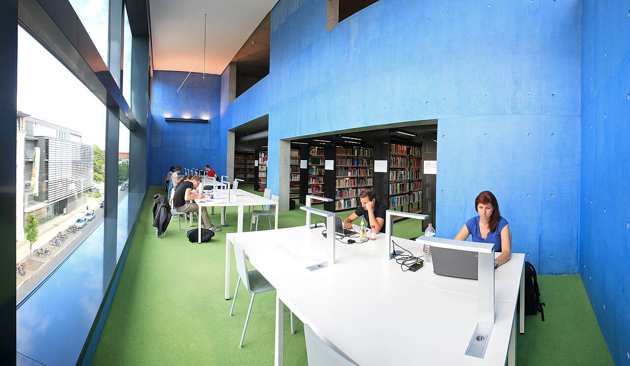 Students sit at large desks in the library