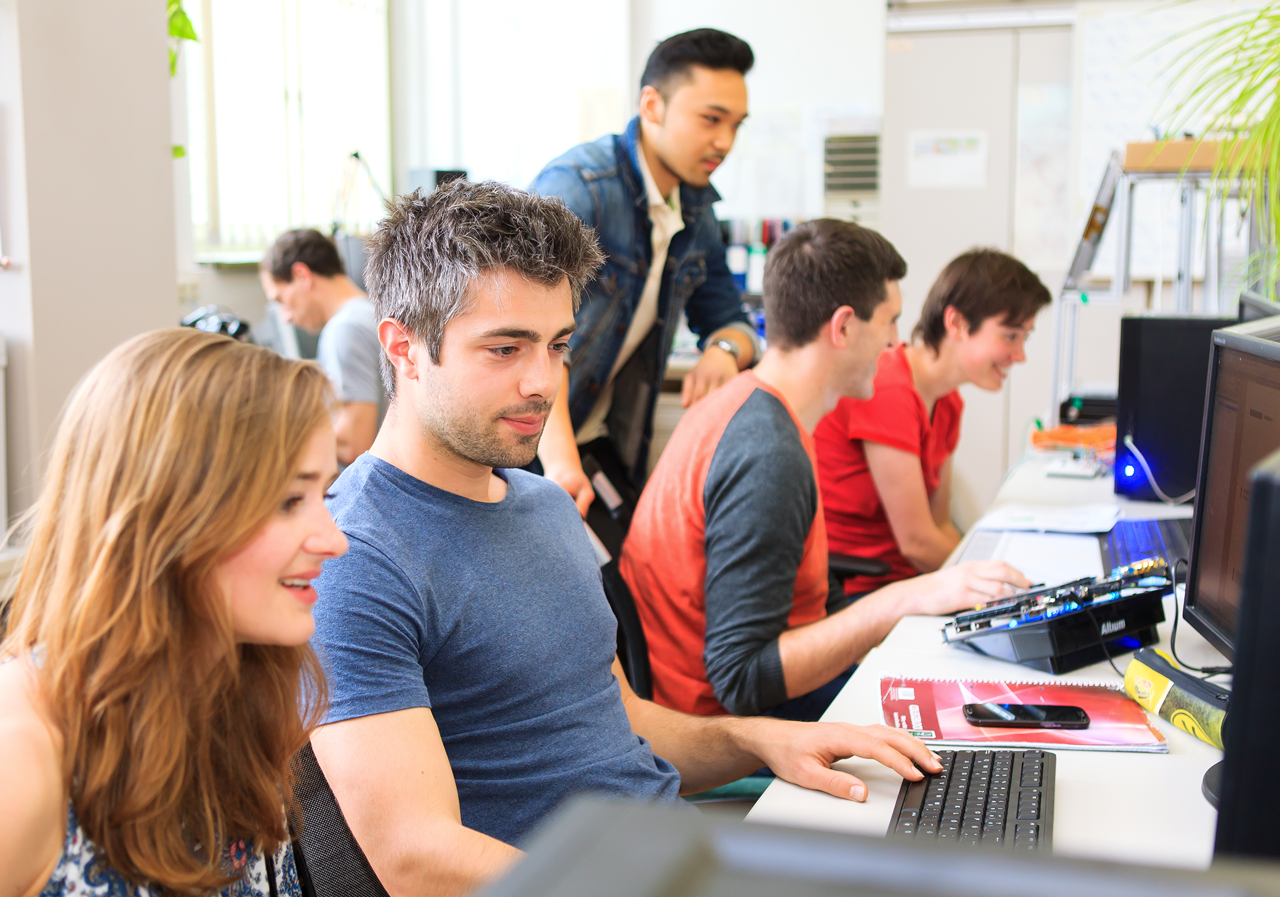 Studierende arbeiten in kleinen Gruppen gemeinsam am Computer