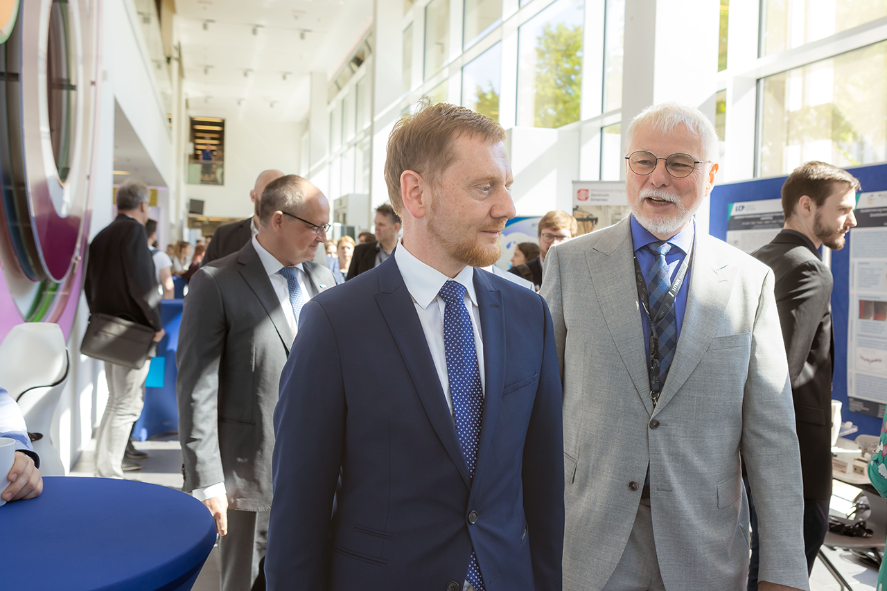 Ministerpräsident Michael Kretschmer und Tagungsleiter Prof. Peter Schulze gehen über Industrieausstellung 3D-Druck Forum 2023