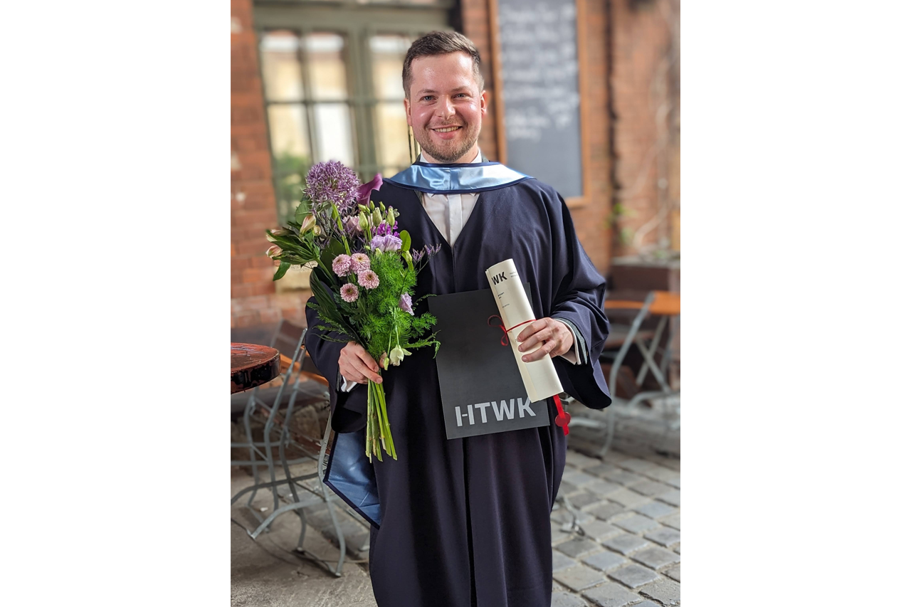 Portraitfoto von Sebastian Walther mit Blumen und Urkunde