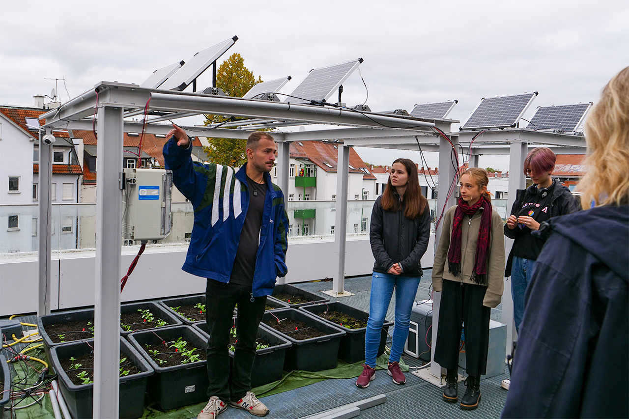 Foto von Teilnehmenden vor Agri-PV Anlage auf dem Dach