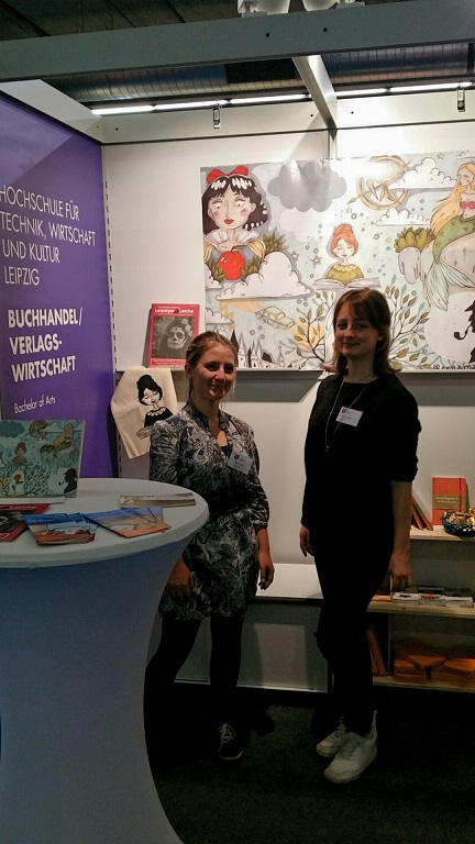 Zwei junge Frauen stehen an einem Messestand. 