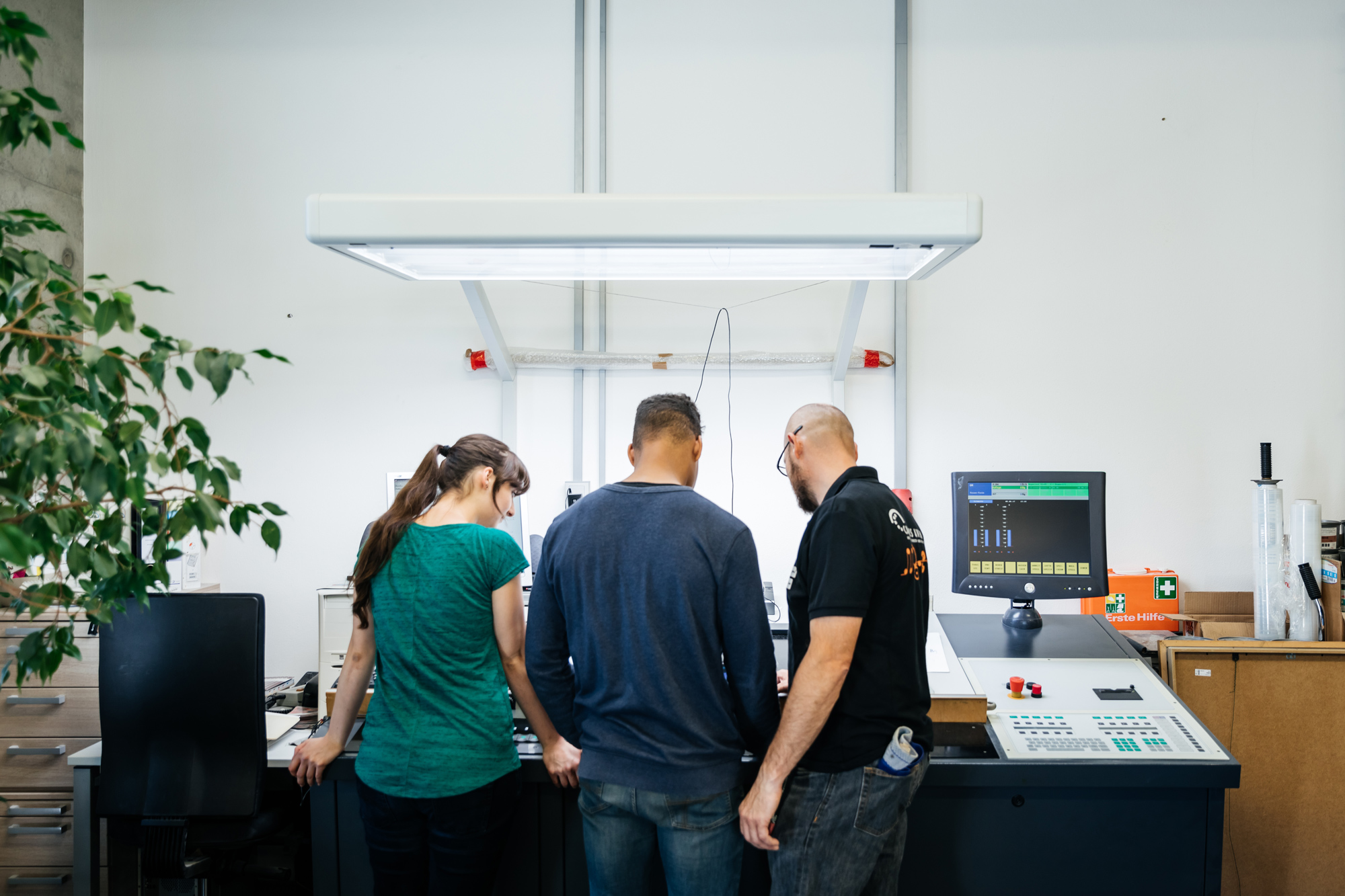 Drucksaal (Foto: feinesbild) Drei Personen stehen an einer großen Druckmaschine
