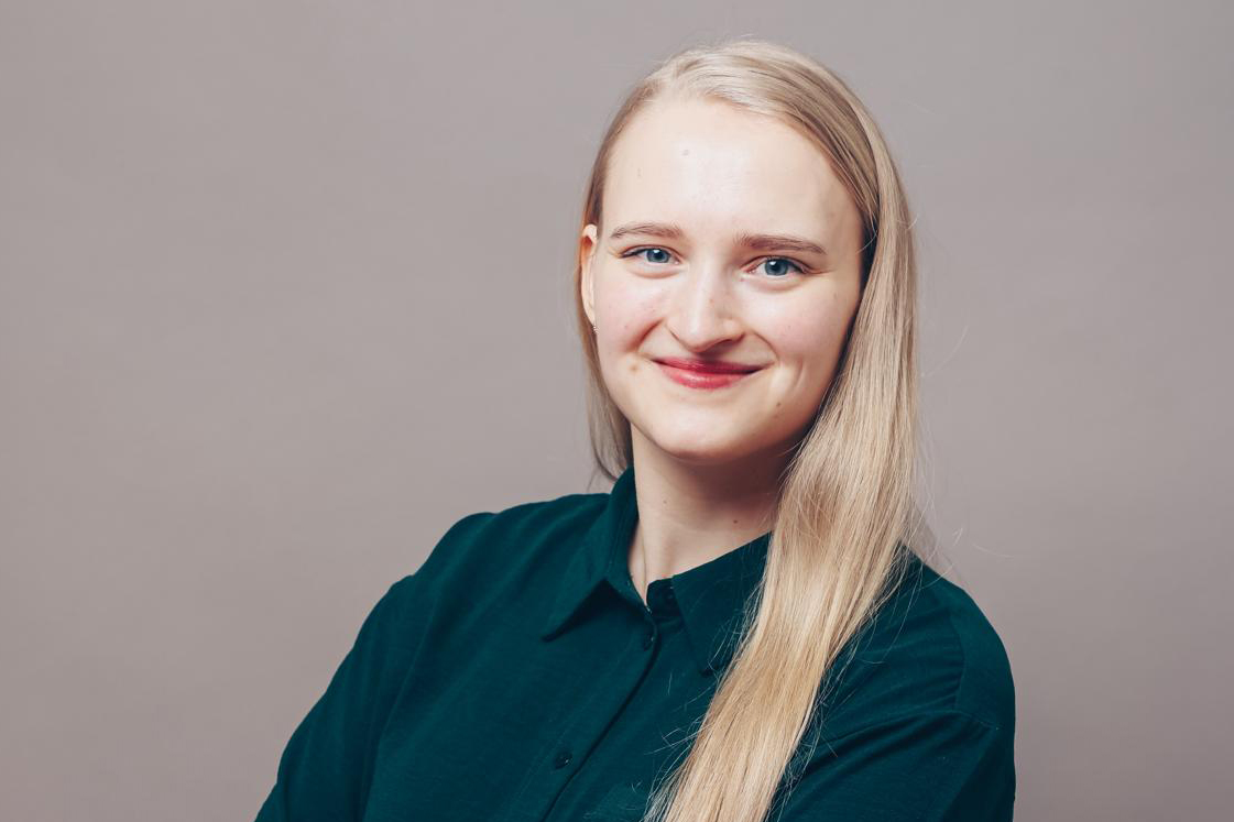 lächelnde Frau mit blonden Haaren und grünem Oberteil