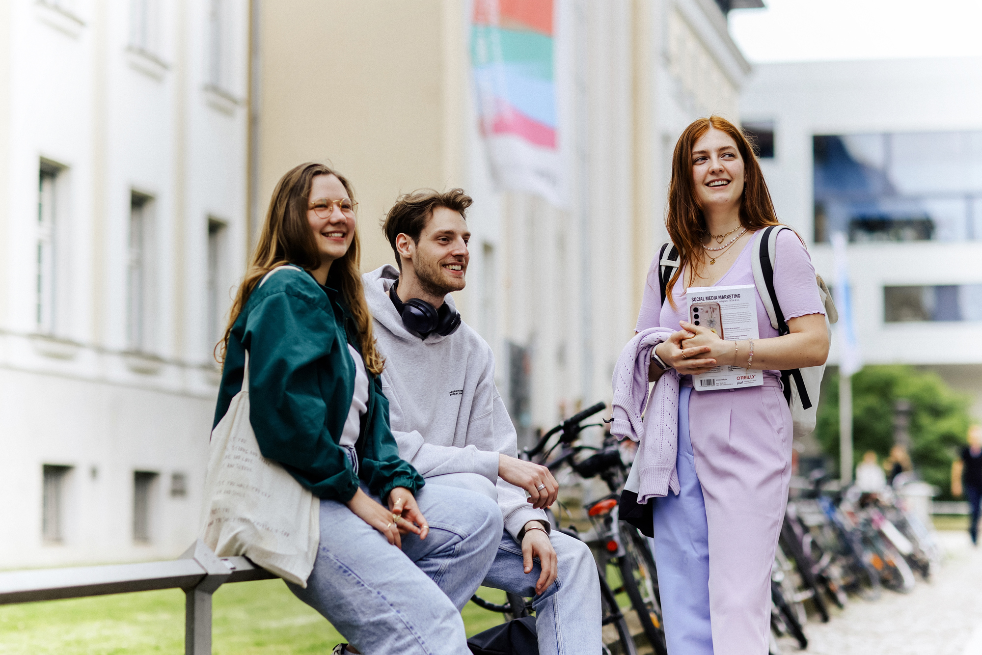 Studierende Drei lächelnde Studierende vor einem HTWK-Gebäude mit Regenbogenflagge