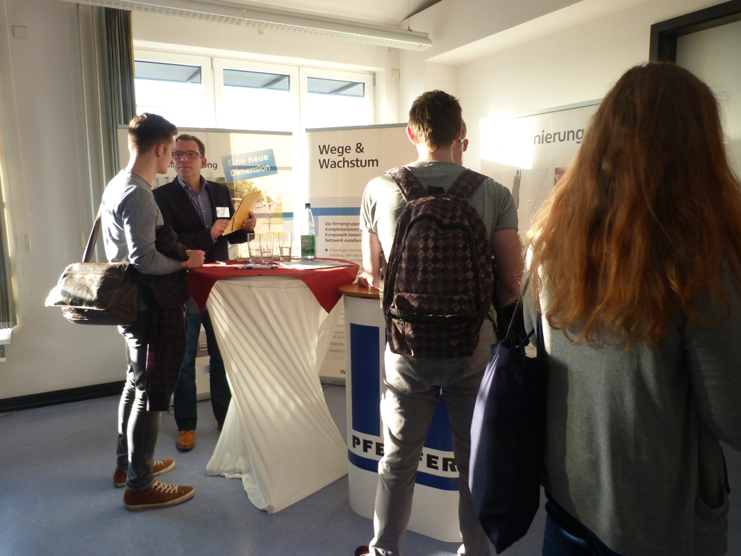 Student unterhält sich mit einem Mitarbeiter eines Kooperationsunternehmens.